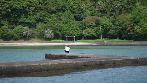 Lone figure sits contemplative on a stone pier Stock Footage 339842524