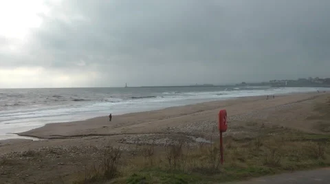 Lone figure walks on desolate beach,  windy winter day with choppy sea Stock Footage 1097554