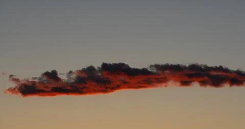 Lone fractus cloud study, a deep fiery crimson, as darkness falls. Stock-Fotos
