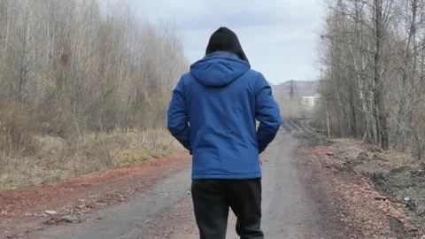 A lone hooded man walks down the road. Stock Footage 153375889