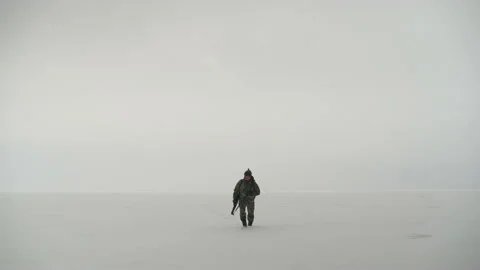 A lone hunter walks through the snow-covered valley Stockbeeldmateriaal 169098429