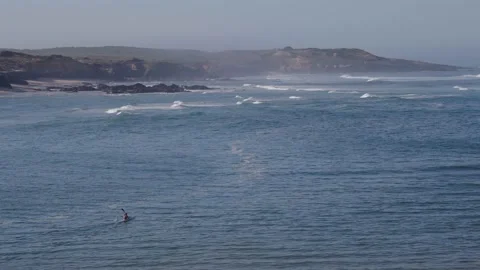 Lone kayaker paddling at sea in front of a hazy rocky coastline, Portugal Video stock 346374445