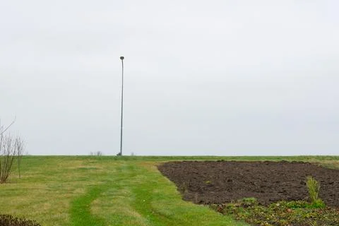 A lone light pole with grass in the foreground and a depressed day. Stock Photos