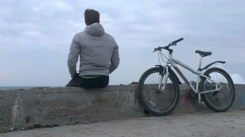 A lone man with bicycle sits on old high concrete pier during huge storm. Stock Footage 68322035
