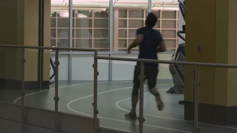 Lone Man Jogs on Indoor Track at Gym while Social Distancing during Workout Stock Footage 136908669