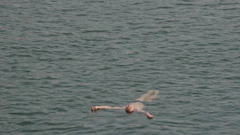 Lone man relaxing while floating on water Stock Footage 333217216