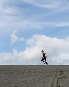 Lone man running on the sand through sandy desert Stock Photos