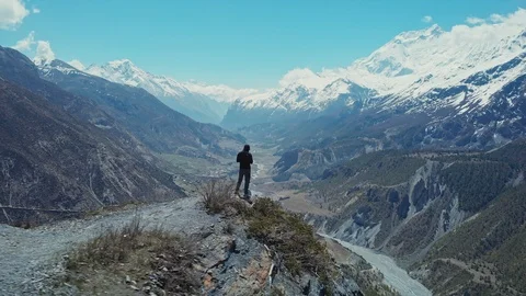 Lone man standing on high cliff at edge of abyss above deep mountain river gorge Stock Footage 126720854