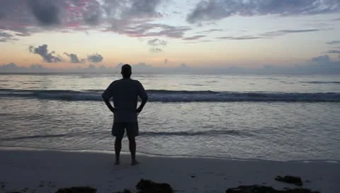 Lone Man Stands on Beach at Sunrise  (HD) Video stock 9870580