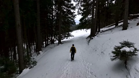 Lone man walking through snow. Mountain expedition. Epic Aerial steady view Video stock 205096912