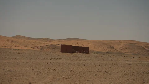 Lone mud brick hut standing in vast Sahara desert plain under hazy sky in Stock Footage 335960058