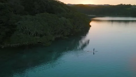 Lone Paddle boarder exploring a quiet estuary at sunset Stock-Footage 187370583
