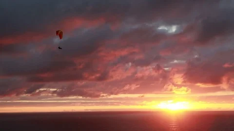 A lone paraglider gently glides over a stormy ocean sunset Stock Footage 82002190