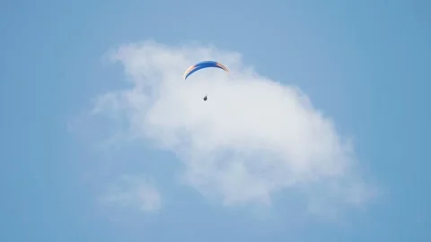 A lone paraglider soars through the skies on the parachute. Pan follow. Video stock 281006793