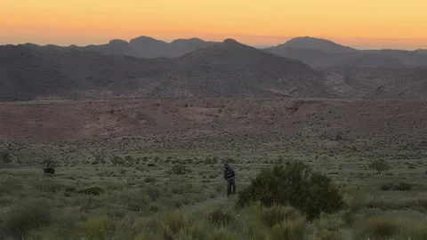 Lone Person Walking Through Desert Mountains at Sunset Video stock 333415902