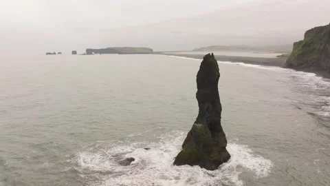 A lone Reynisdrangar sea stack rises from the ocean off Reynisfjara beach Stock Footage 286933707