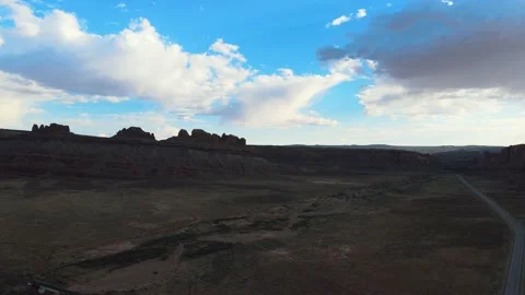 Lone Road through Desert Red Rock Formations Against Blue Sky Drone Stock Footage 154131578