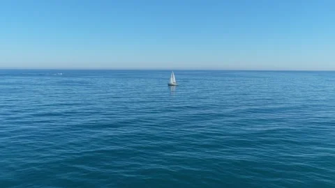 Lone sailboat navigating the vast blue ocean 動画素材 330420796