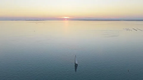 Lone sailboat sailing during a serene sunset over the zeelandbrug Stockbeeldmateriaal 342809571