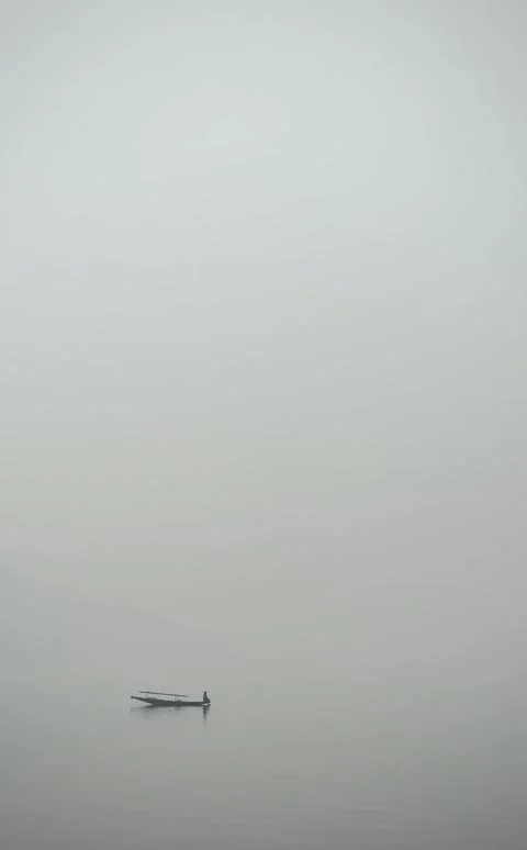A lone shikara glides through winter mist on Dal Lake, Kashmir Stock Footage 323802673