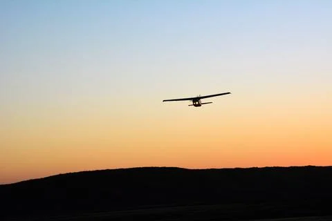 A lone small single-engine plane flies in the clear evening sky Stock Photos