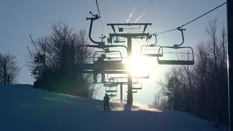 A lone snowboarder rides the lift at a ski hill Stock Footage