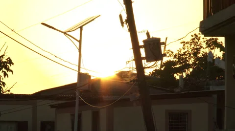 Lone solar panel, sunset behind, amid jumble of power lines Stock Footage 39454684