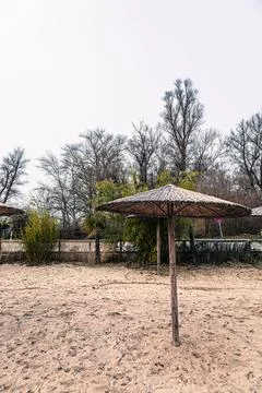 A lone straw umbrella stands on a sandy beach, hinting at warmer days amidst  Foto stock