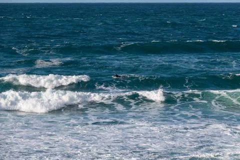A lone surfer facing the waves on the Cornish coast Stock Photos