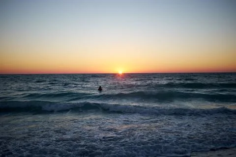 Lone surfer on the waves at sunset Stock-Fotos