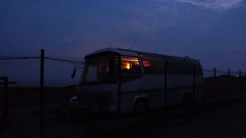 A lone white bus one alone stands behind an iron fence in an enclosed parking lo Stock Footage 126922937