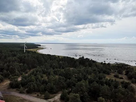 Lone wind generator among the trees on the seaside on a cloudy day Stock Photos