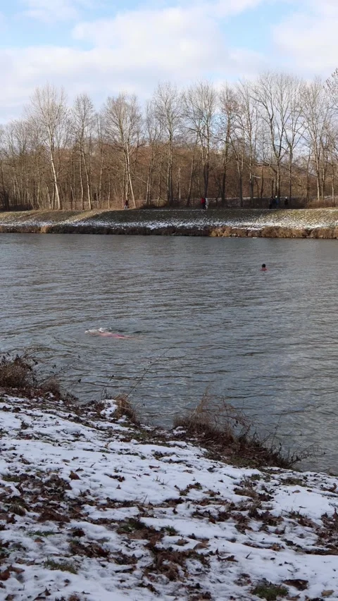 Lone winter swimmer practicing cold water hardening in a frosty river Stock Footage 329632724