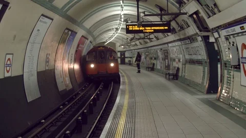 A lone woman walks down an empty tube train station as a train arrives Stock-Footage 82804802
