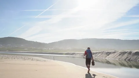 Lonely backpacker man walking along sandy beach washed by Atlantic Ocean waves i Stock-Footage 310905109