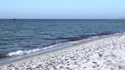 Lonely beach on baltic coast. Blue sky, bright sun. Small sea waves with boat. Stock Footage 155096736