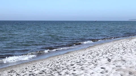Lonely beach on baltic coast. Blue sky, bright sun. Small sea waves with boat. Stock Footage 155096745