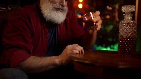 Lonely bearded man in his 50s drinks liquor, coping with Christmas depression Stock Footage 342520474