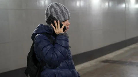 Lonely boy in hat and jacket talking on phone in underground covered passage in Stock Footage 168243547