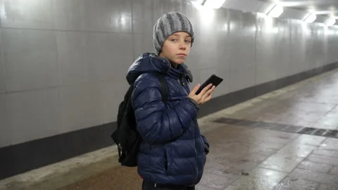 Lonely boy in hat and jacket talking on the phone in underground covered passage Stock Footage 168542353
