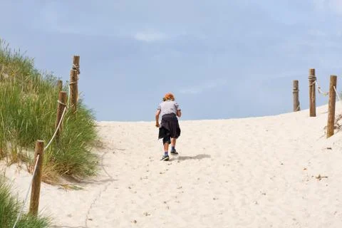 Lonely boy walking through a sand dune Fotos Stock