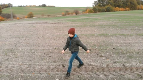 The lonely boy wanders in autumn in an empty, plowed, gray field. The croaker is Stock Footage 106528176