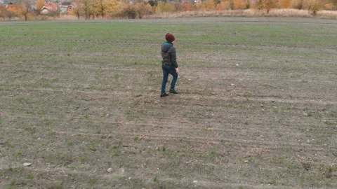 The lonely boy wanders in autumn in an empty, plowed, gray field. The croaker is Stock Footage 106530252