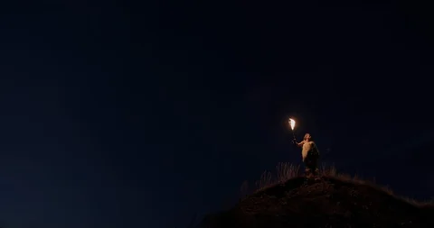 Lonely brave fighter explorer with lighted torch on high hill against dark Stockbeeldmateriaal 130009900