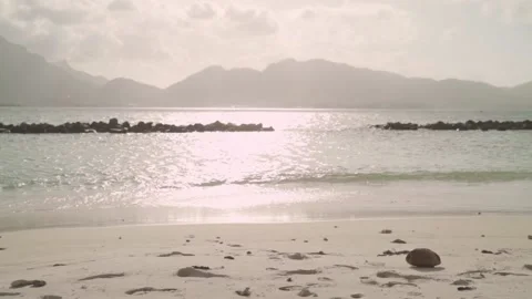 Lonely brown coconut lying washed up on shore with sandy beaches and islands Stock Footage 192925823