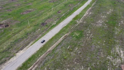 A lonely car drives along an empty road outside the city in the countryside Stock Footage 193976378