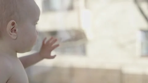 Lonely child looking through window lost in contemplation of bustling street Stock Footage 271690791