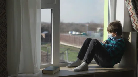 Lonely child with mask sit at window in home, sadness in isolation Vidéo 150724745