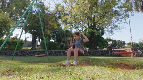 Lonely Child Sits on a Swing in a Quiet Park Setting Stock Footage 335985556