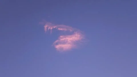 A lonely cloud floats in the blue sky in the rays of the setting sun Stock Footage 313754122